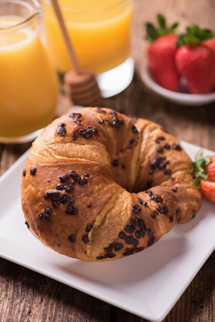 Frühstück, Orangensaft und frische Schokoladen-Criossants auf dem Tisch