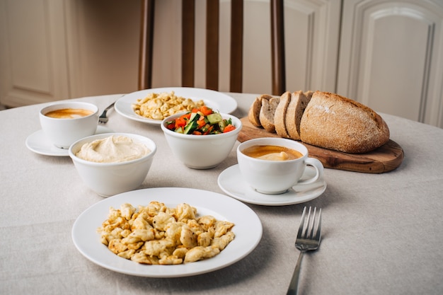 Frühstück. Rührei oder Omelett, Hummus, Kaffee, Gemüsesalat, Brot. Esstisch