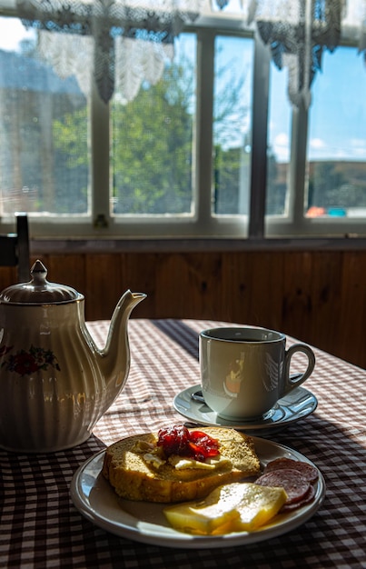 Frühstück serviert mit Käse Marmelade Butterbrot Salami auf dem Tisch mit karierter Tischdecke