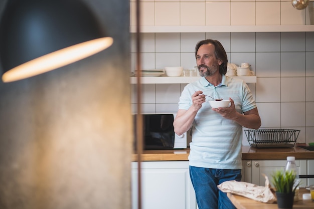 Frühstück zu Hause. Reifer Mann, der frühstückt und zufrieden und friedlich aussieht