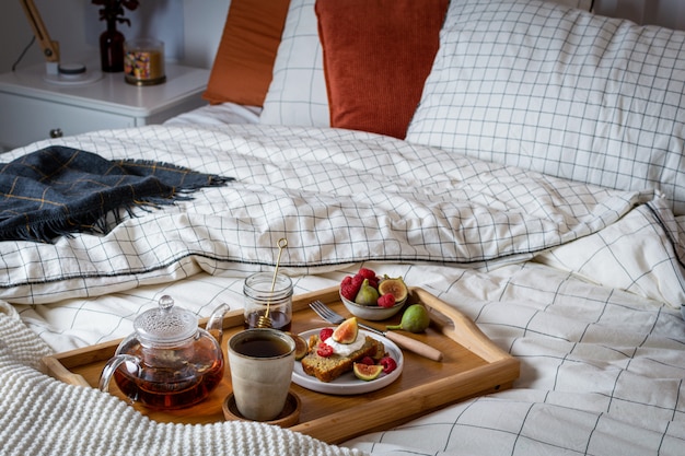 Frühstücken Sie im Bett mit Gebäck und frischen Früchten, schwarzer Tee
