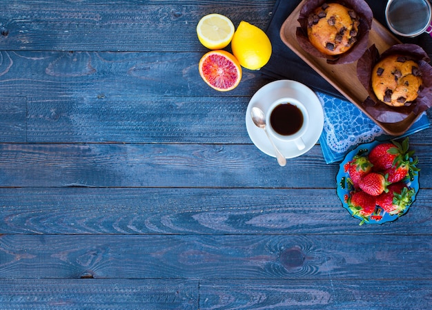 Frühstücken Sie mit Kaffee und Tee mit unterschiedlichem Gebäck und Früchten auf einem Holztisch