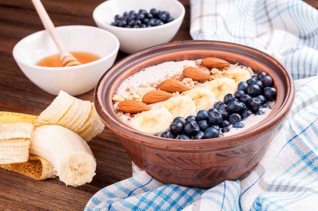 Frühstücken Sie mit Smoothieschüssel mit Banane, Blaubeeren, Mandel und Honig