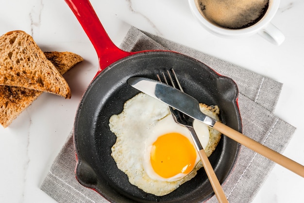 Frühstücken Sie mit Toastbrot, Spiegelei auf Eisenwanne und Kaffee auf weißer Marmorszene