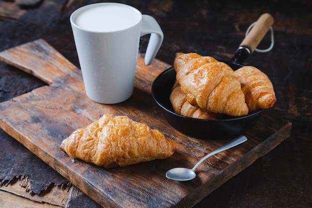 Frühstücksbrot, Croissants und frische Milch auf dem Holztisch.