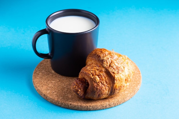 Frühstücksbrot und eine Tasse Milch auf gelbem und blauem Hintergrund