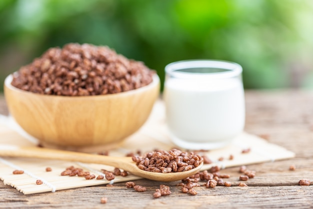 Frühstücksflocken, Puffreis mit Kakao in der Schüssel und Glas Milch auf Holztisch