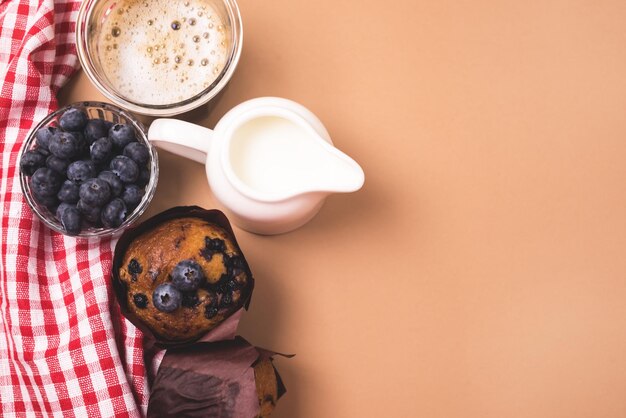 Frühstückskonzept Hausgemachte Muffins mit Blaubeerkaffee und Milch serviert auf braunem Hintergrund Kopierraum