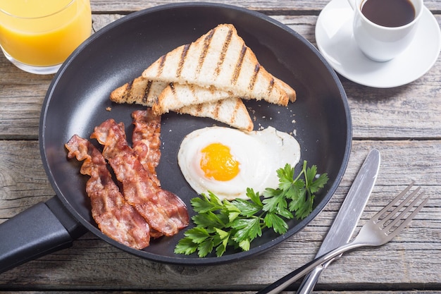Frühstückspfanne mit Eiern, Speck und Toast. Lebensmittelhintergrund
