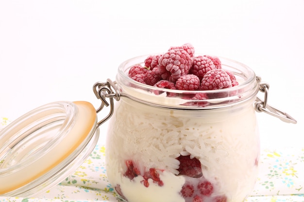 Frühstücksreisbrei mit Vanillesoße, gefrorene Himbeeren in einem Glasgefäß