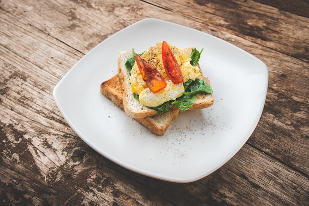 Frühstückssandwich mit Ei, Brunnenkresse und Tomate auf dem Holztisch, gesundes Lebensmittel