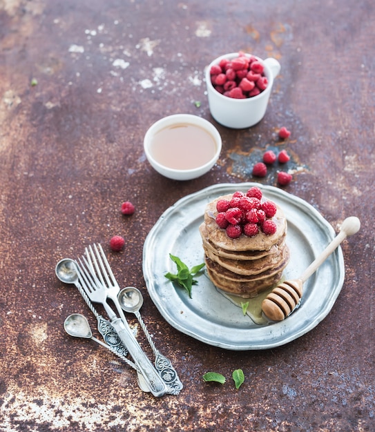 Frühstücksset. Buchweizenpfannkuchen mit frischen Himbeeren, Honig und Minze über Schmutzmetall