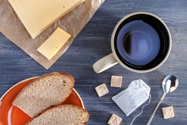 Frühstückstee mit Käse, Brot auf Holztisch. Ansicht von oben