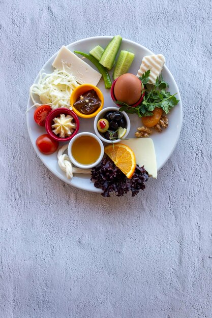 Frühstücksteller mit gekochten Eiern, Schokolade, Käse, Honig, Tomaten, Gurken, Oliven und Gemüse