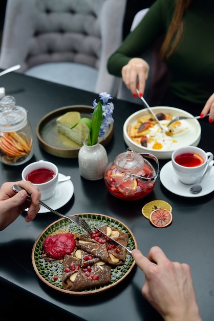 Frühstückstischeinstellung mit Pfannkuchen, Tee. Paar isst