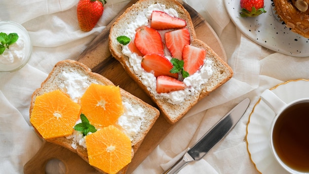 Frühstückstoast mit frischen Früchten Vollkornbrot Erdbeeren Orangen und hausgemachtem Frischkäse