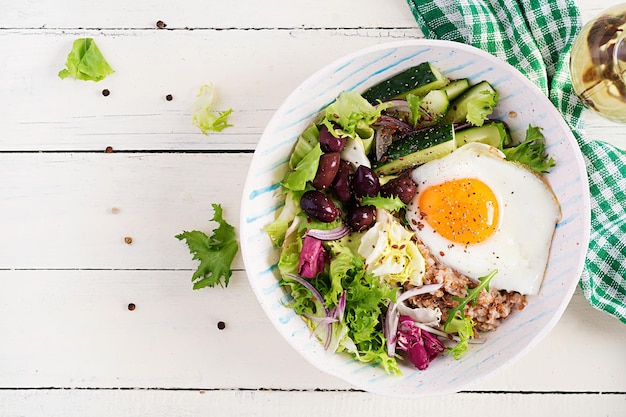 Frühstücksweizenbrei mit gerösteten Eiergurken und Oliven Gesundes, ausgewogenes Essen Draufsicht flach gelegt