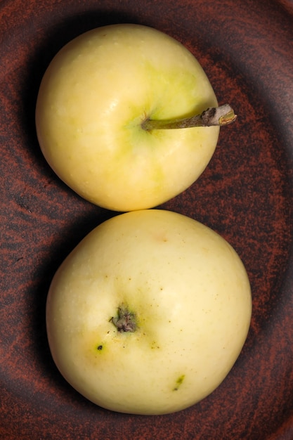 Fruitimagem maçã doce madura branca em um prato de argila marrom close-up macro fotografia