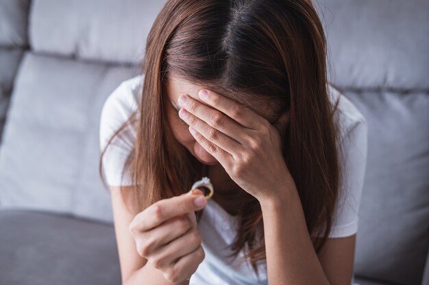 Frustrada esposa triste quitándose el anillo de bodas, pareja joven rompiendo el concepto de divorcio