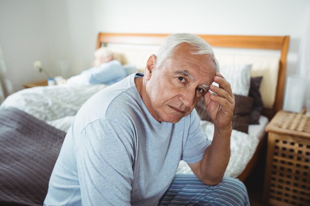 Frustrado homem idoso sentado na cama