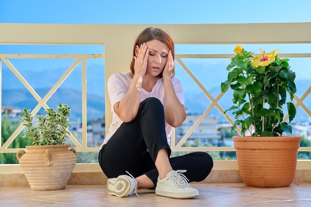 Frustrierte, depressive, einsame Frau mittleren Alters, die ihren Kopf mit den Händen hält