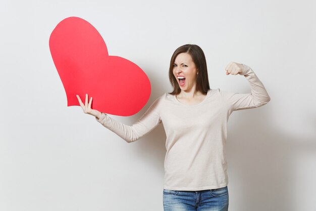 Frustrierte junge starke Frau, die großes rotes Herz in den Händen lokalisiert auf weißem Hintergrund hält. Kopieren Sie Platz für Werbung. Mit Platz für Text. Valentinstag- oder Internationaler Frauentag-Konzept.