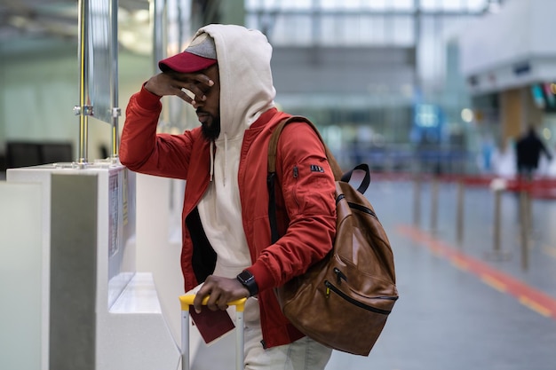 Frustrierter enttäuschter afroamerikanischer männlicher Passagier mit Gepäck verschlafen und Flug verpasst