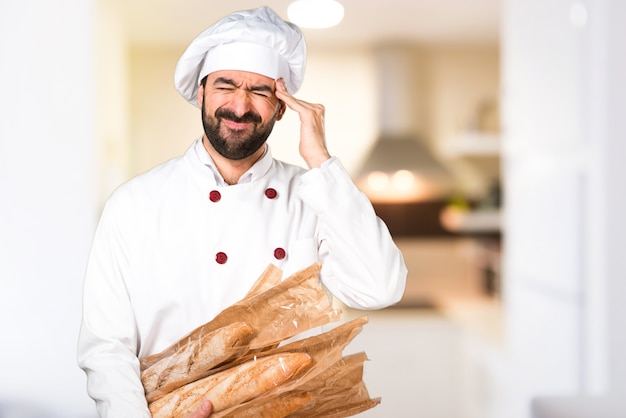 Frustrierter junger Bäcker, der etwas Brot in der Küche hält