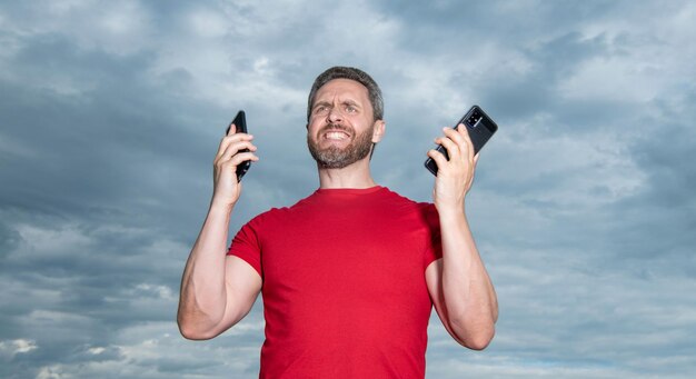 Foto frustrierter mann hat ein telefongespräch trage ein rotes t-shirt foto von mann hat ein telefongespräch mann hat ein phone-gespräch auf dem himmel hintergrund mann hat ein telefongespräch im freien