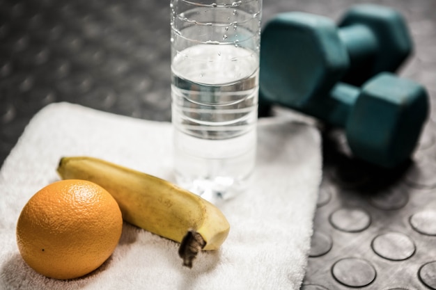 Foto fruta, agua y mancuernas en el gimnasio de crossfit.