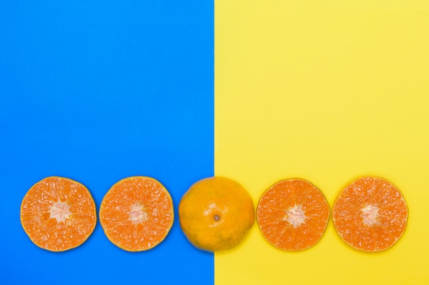 Fruta anaranjada cortada a medias en fondos azules y amarillos.