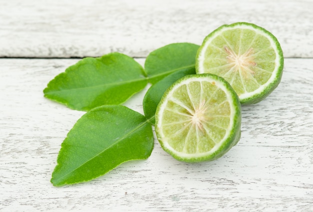 Fruta bergamota con hojas verdes en madera blanca