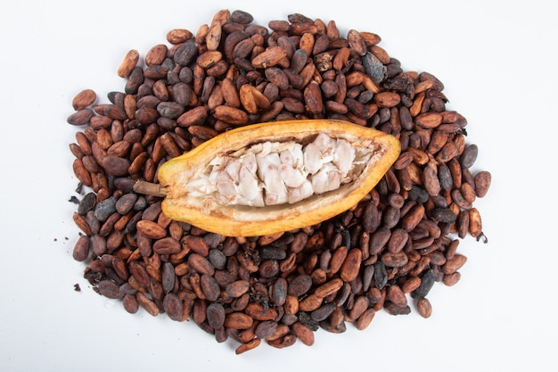 Foto fruta de cacao cortada con granos de cacao crudos sobre un fondo blanco.