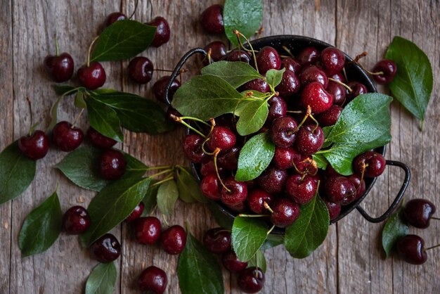 Fruta de cereza oscura madura fresca con hojas verdes