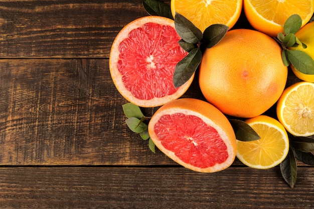 Fruta cítrica. Varias frutas cítricas con hojas de limón, naranja, pomelo en una mesa de madera marrón. vista superior