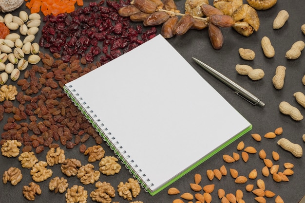 Fruta confitada, Frutos secos Nuez, cuaderno, bolígrafo. Refrigerio nutritivo para adelgazar y aumentar la inmunidad. Aptitud de alimentos saludables. . Endecha plana