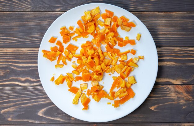 Fruta confitada en el plato. Naranjas caseras secas. Fondo de madera.