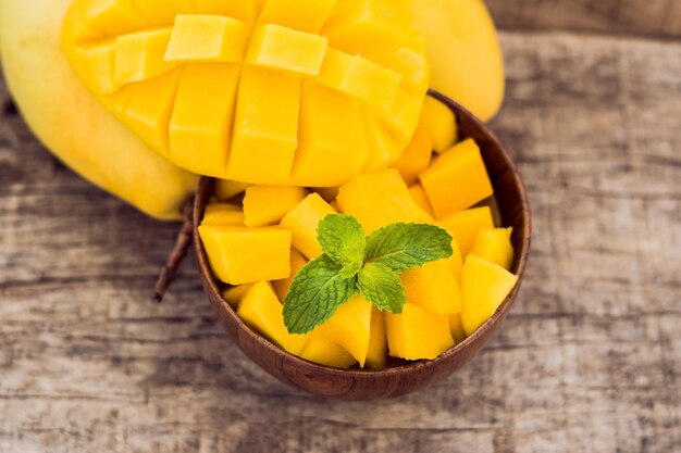 Fruta da manga e cubos de manga na mesa de madeira