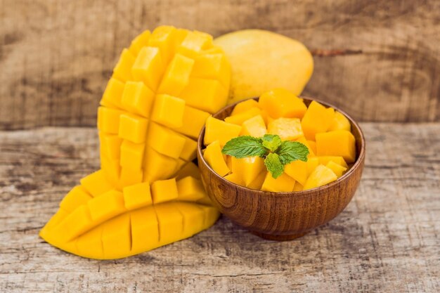 Fruta da manga e cubos de manga na mesa de madeira