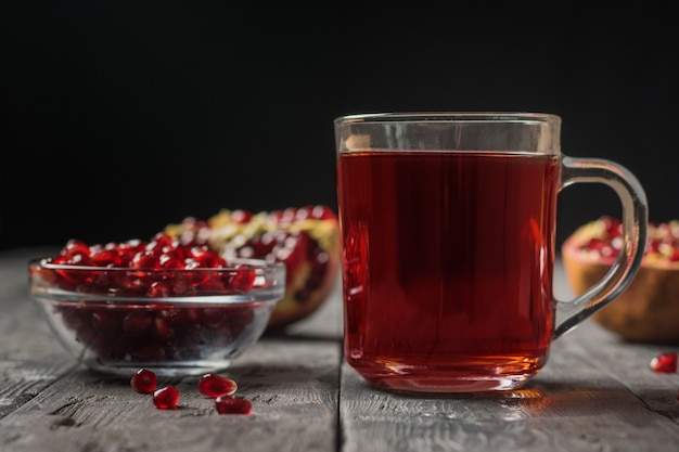 Fruta da romã fresca e suco de romã em uma caneca de vidro sobre uma mesa de madeira. bebida útil para a saúde.