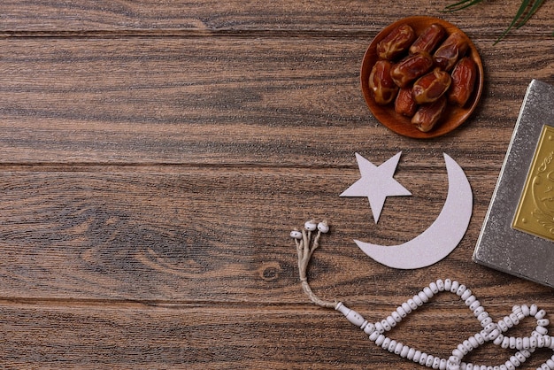 Fruta de dátiles con cuentas de oración y decoración islámica sobre fondo de madera