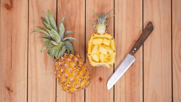 Fruta de abacaxi e seus pedaços em um fundo de madeira