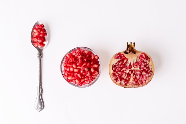 Fruta de romã cortada ao meio em uma tigela de vidro e uma colher de sopa de sementes de romã