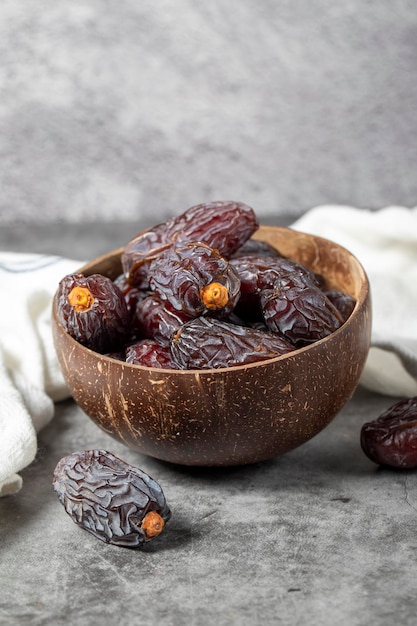 Fruta de tâmaras de Jerusalém em fundo de pedra Fruta de támaras enorme em uma tigela de coco Alimentação do Ramadão Alimentação saudável de perto