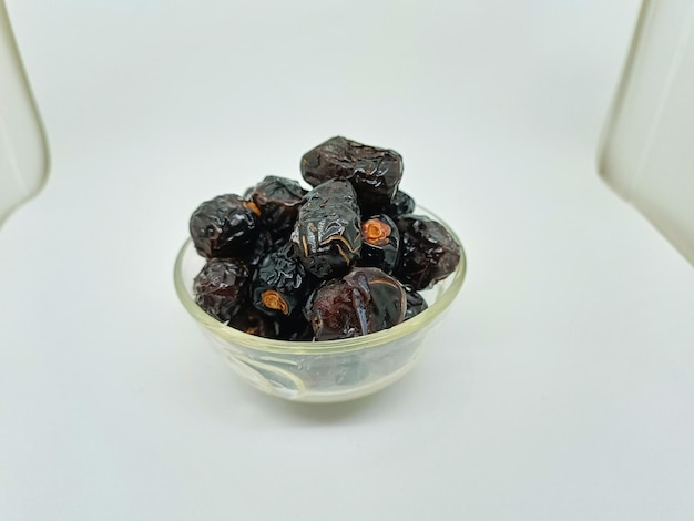 fruta de tamareira isolada em fundo branco tâmaras secas em tigela de vidro