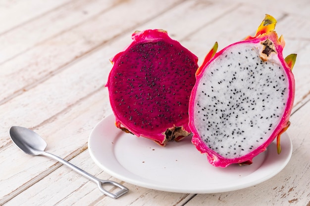 Fruta do dragão vermelha fatiada, fruta do dragão da Costa Rica, pitaya roxa, cacto de pêra morango e fruta do dragão branco em placa de cerâmica branca sobre fundo de textura de madeira velha branca com espaço de cópia, pitahaya