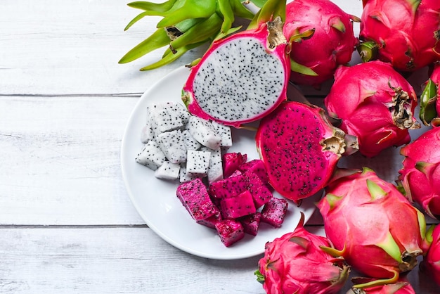 Foto fruta de dragón púrpura roja blanca y rosada fresca tropical en el concepto de fruta saludable de tailandia asiática rebanada de fruta de dragón y cortada a la mitad en un plato blanco con fondo de pitahaya