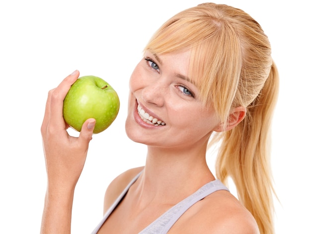 La fruta es la mejor merienda Retrato de estudio de una atractiva mujer joven sosteniendo una manzana aislada en blanco