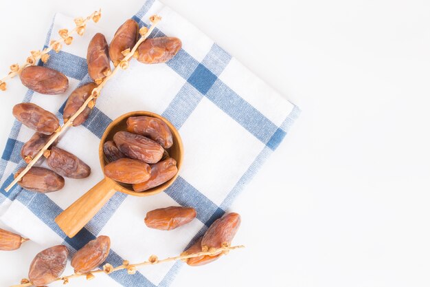 Fruta de las fechas en la cucharón de madera en el fondo blanco, opinión superior de las frutas de la palma datilera