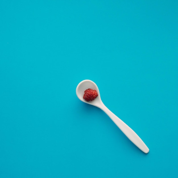 Fruta de frambuesa jugosa en una cuchara de medicina blanca en lugar de medicina